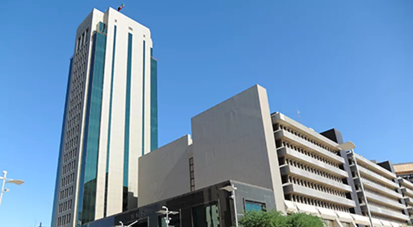 Sahab Tower in Kuwait, a tall, modern office building with a sleek glass façade, standing prominently against a clear blue sky alongside surrounding government and commercial buildings.
