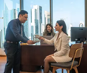 A modern office at Sahab Tower, Kuwait, where a team interacts in a bright, high-rise setting with panoramic city views in the background.